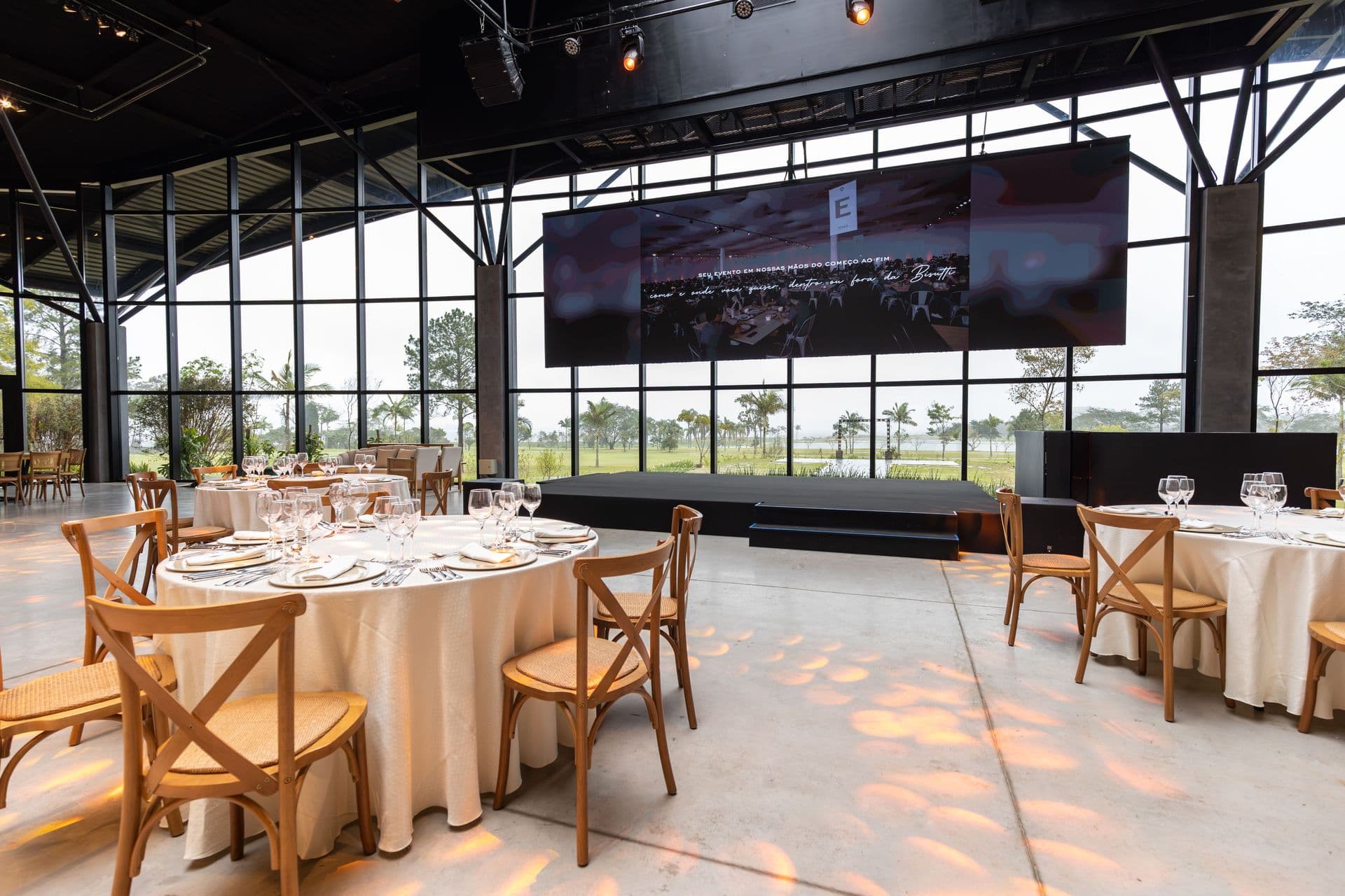 Banquet room set for a corporate dinner with a stage, wide LED screen and rigged lighting