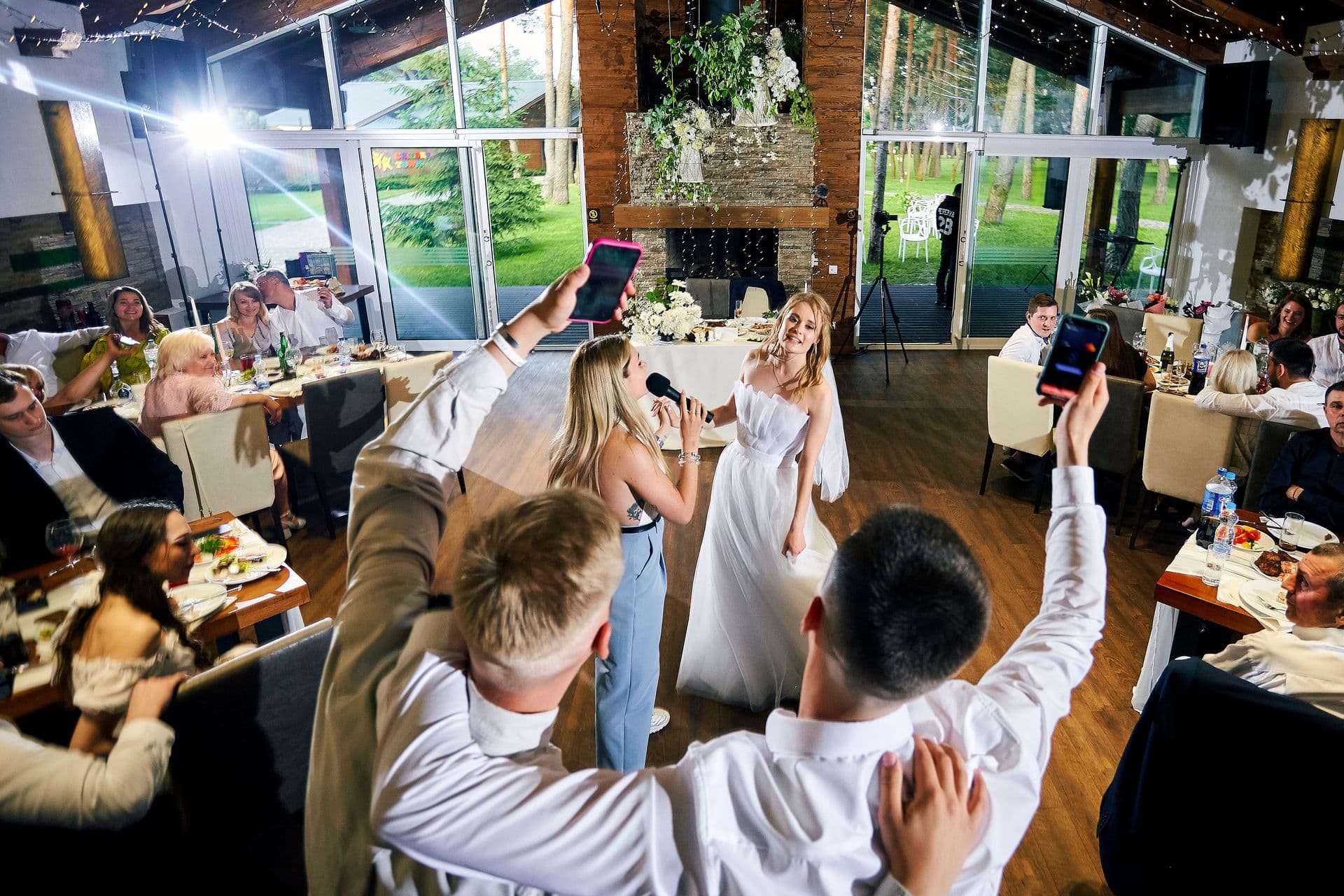 Guests raising phones and glasses during a toast