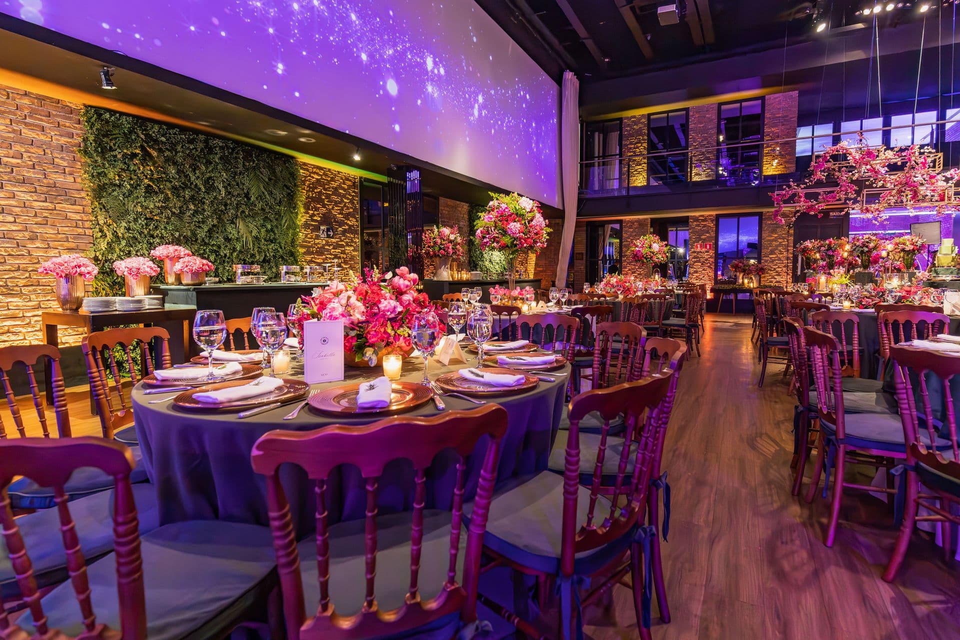Banquet room dressed with florals under purple up-lighting