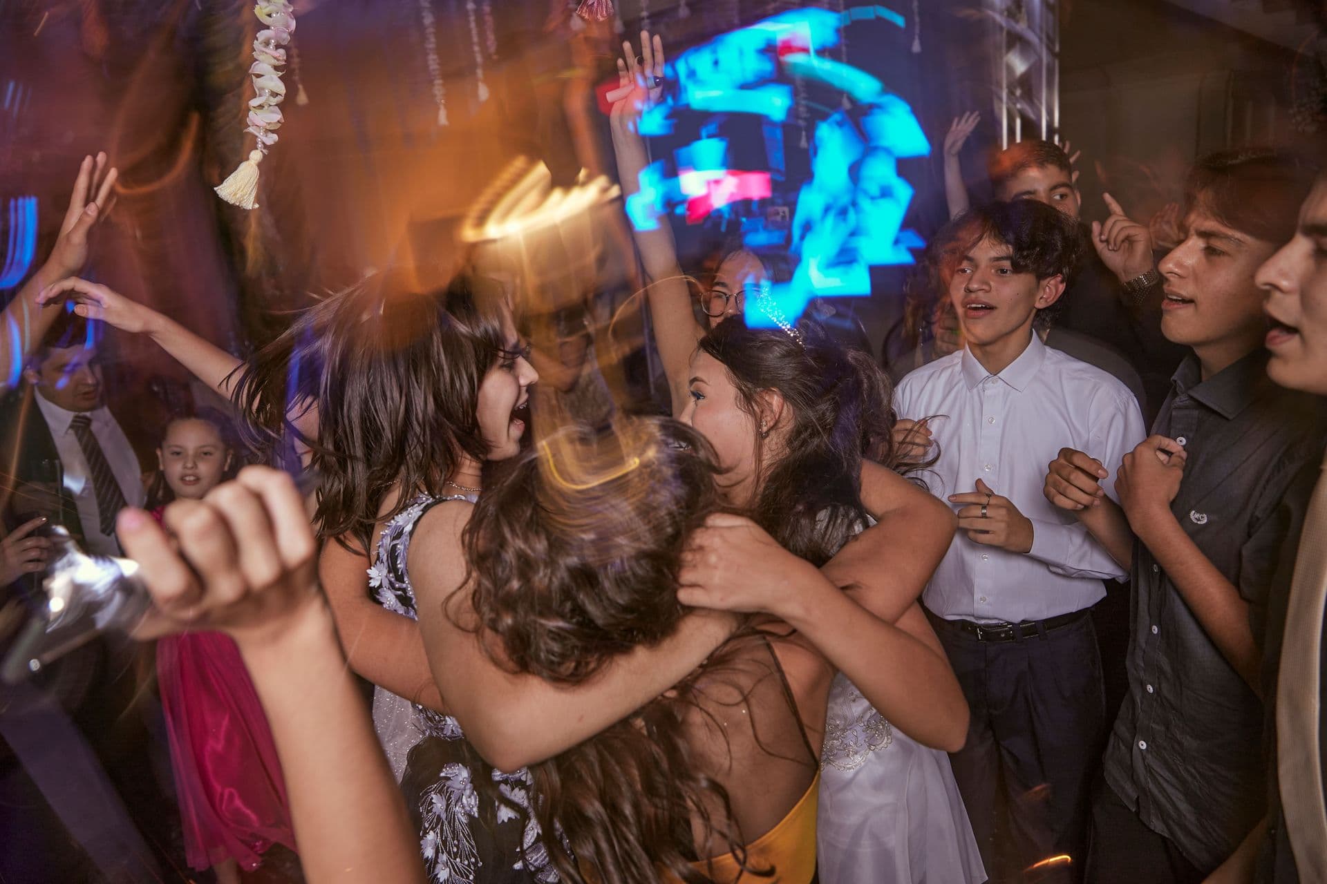 Students in formalwear packed onto a prom dance floor under moving lights
