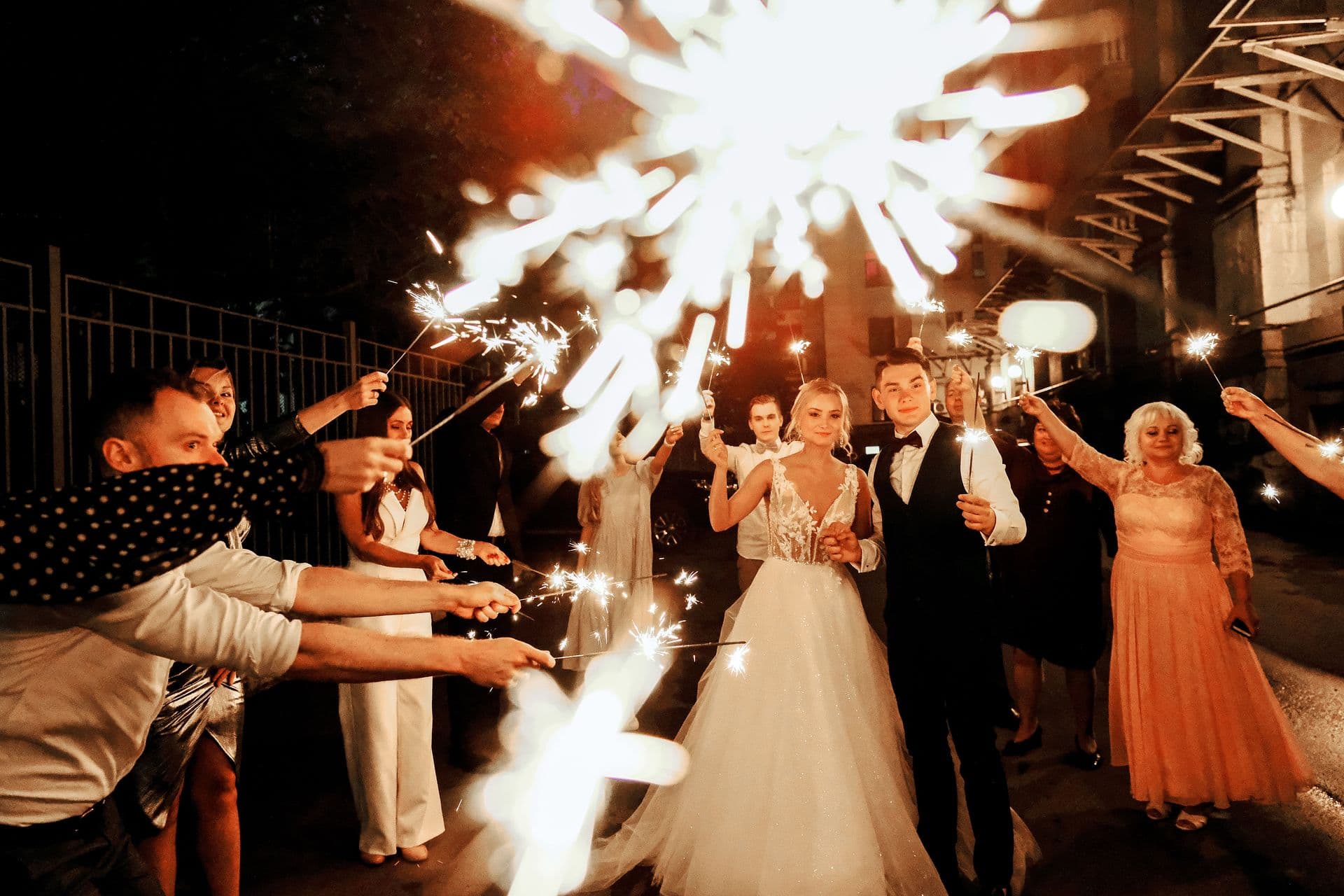 Couple exiting through a sparkler tunnel held by guests